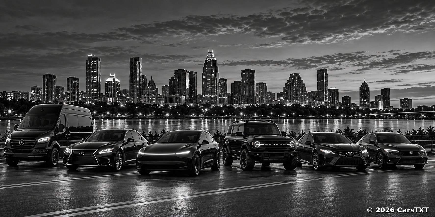 A lineup of vans, sedans and SUVs parked by a lake with a city skyline at night